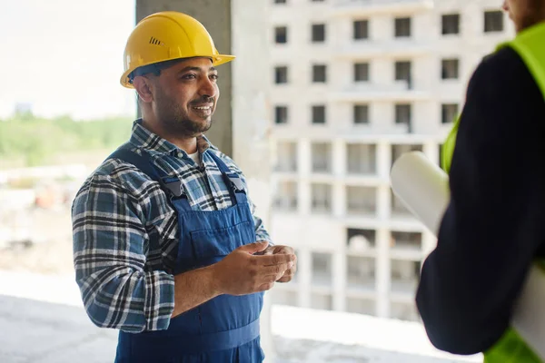 Dos ingenieros discuten preguntas relacionadas con el trabajo juntos manteniendo un plano plegado . — Foto de Stock