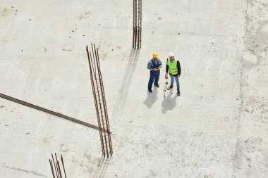 Üniformalı iki mühendis yukarıdan çekilen işle ilgili soruları tartışıyor..