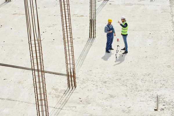 Dos ingenieros en uniformes discuten preguntas relacionadas con el trabajo juntos disparados desde arriba . — Foto de Stock