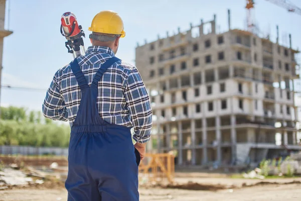 Un ingegnere sul punto di costruzione detiene attrezzature relative al lavoro . Fotografia Stock