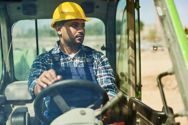 An engineer in uniform drives a green tractor.