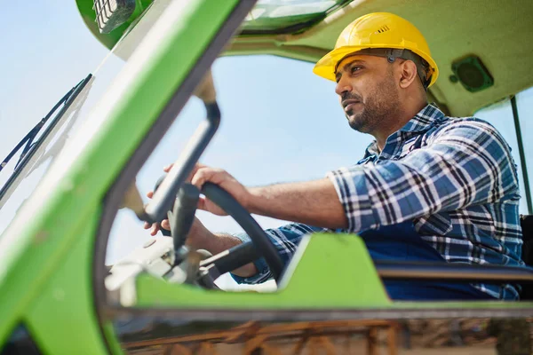 An engineer in uniform drives a green tractor. — ストック写真