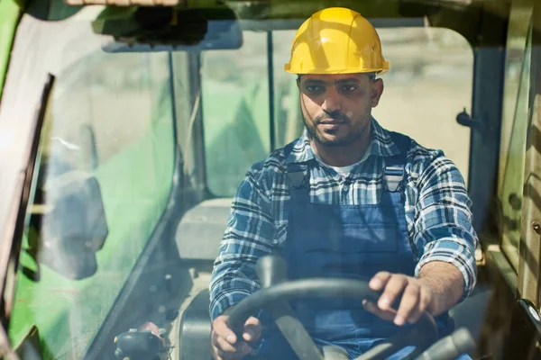 An engineer in uniform drives a green tractor. — ストック写真