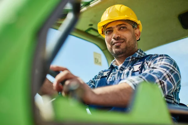 An engineer in uniform drives a green tractor. — ストック写真