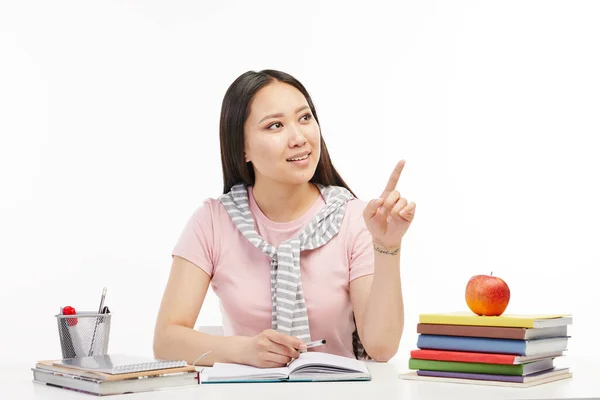 Asian student sits at the table with a book in front of her. — Stock Photo, Image