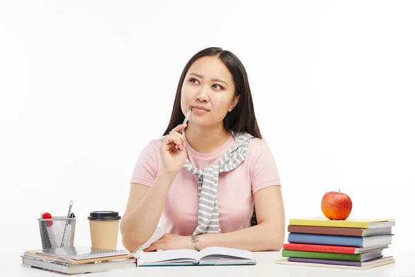 Asiática estudiante se sienta a la mesa con un libro delante de ella . — Foto de Stock