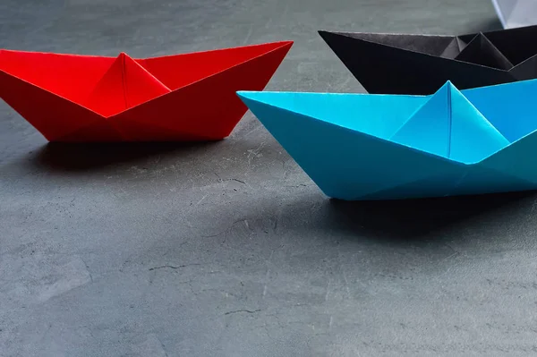 Business leadership Concept, Paper Boat, the key opinion Leader, the concept of influence.Red.blue and black paper boat as the Leader on a gray concrete background — Φωτογραφία Αρχείου