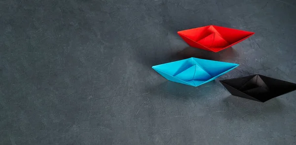 Business leadership Concept, Paper Boat, the key opinion Leader, the concept of influence.Red.blue and black paper boat as the Leader on a gray steel background, copy space, flat lay. — Φωτογραφία Αρχείου