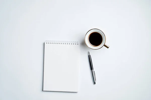 Notepad, kalem ve kahve bardağı ile beyaz ofis masaüstü görünümü, minimal tasarım, üst görünüm, kopyalama alanı, düz uzanma