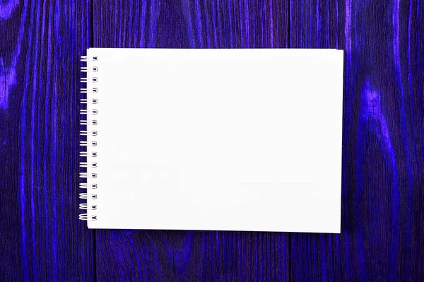 Beyaz ofis Notepad parlak mavi renkli ahşap zemin üzerinde uzanır, minimal tasarım, üst görünüm, düz yatış, kopyalama alanı — Stok fotoğraf
