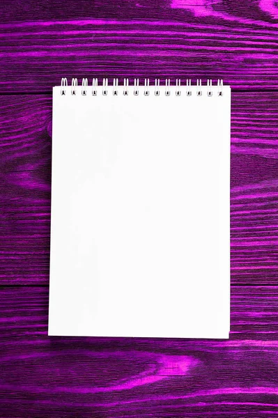 ホワイトオフィスメモ帳は、明るい紫色の木製の背景、ミニマルなデザイン、トップビュー、フラットレイアウト、コピースペースにあります — ストック写真