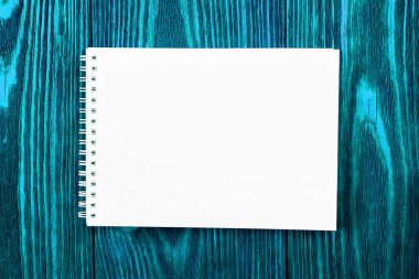 Beyaz ofis Notepad parlak mavi renkli ahşap zemin üzerinde uzanır, minimal tasarım, üst görünüm, düz yatış, kopyalama alanı