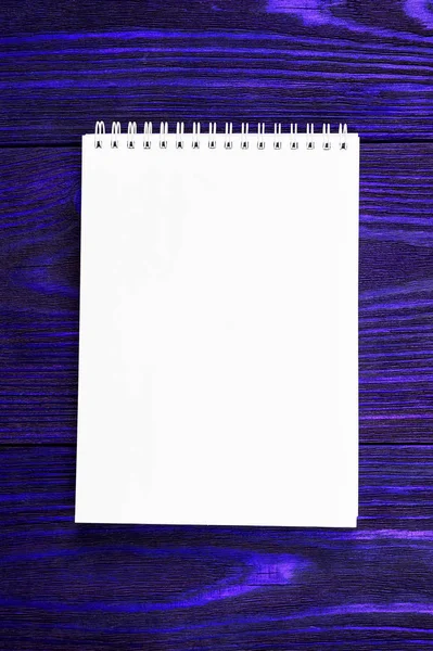 Fehér iroda Notepad fekszik egy fényes fantom kék színű fa háttér, minimalista design, felülnézet, lapos laikus, másolás tér — Stock Fotó