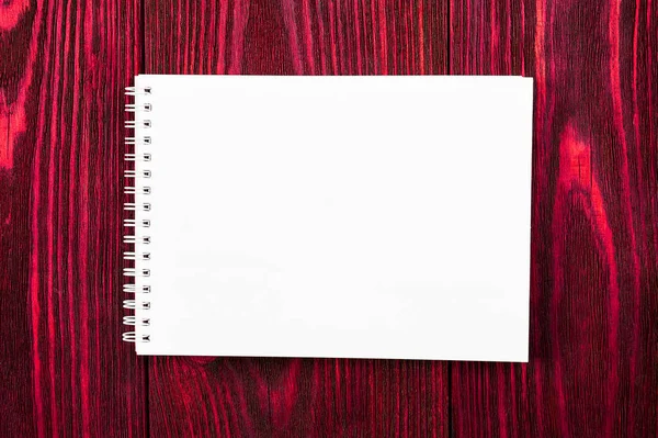 White office Notepad lies on a bright red colored wooden background, minimalistic design, top view, flat lay, copy space — Stock Photo, Image