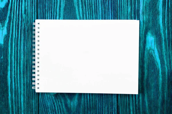 Escritório branco Bloco de notas encontra-se em um fundo de madeira de cor azul brilhante, design minimalista, vista superior, flat lay, espaço de cópia — Fotografia de Stock