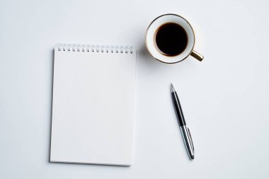 Notepad, kalem ve kahve bardağı ile beyaz ofis masaüstü görünümü, minimal tasarım, üst görünüm, kopyalama alanı, düz uzanma