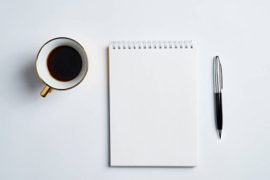 Notepad, kalem ve kahve bardağı ile beyaz ofis masaüstü görünümü, minimal tasarım, üst görünüm, kopyalama alanı, düz uzanma