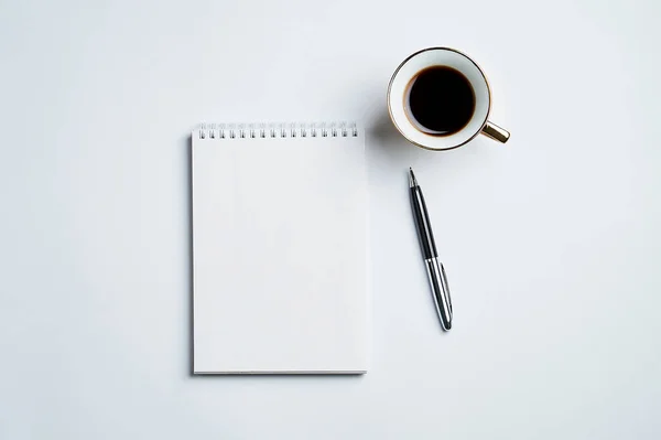 Notepad, kalem ve kahve bardağı ile beyaz ofis masaüstü görünümü, minimal tasarım, üst görünüm, kopyalama alanı, düz uzanma