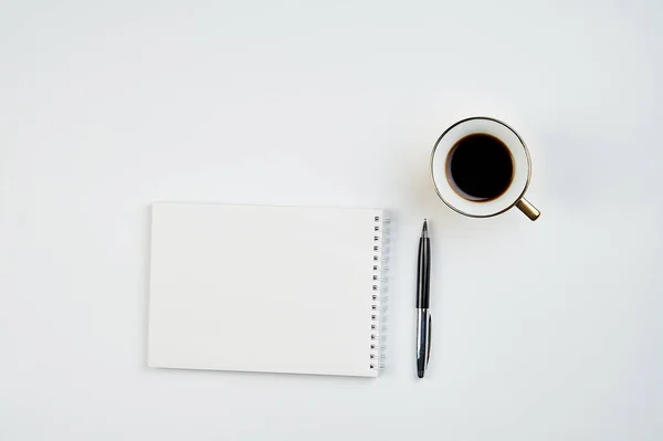 white office Desk top view with Notepad, pen and coffee Cup, minimalistic design, top view,copy space,flat lay