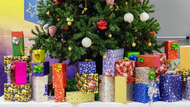 Noel ve yeni yıl tatillerinde, çok sayıda hediye çok renkli bir ambalaj kağıdıyla ağaçta güzel oyuncaklarla büyük bir Noel ağacının altında..