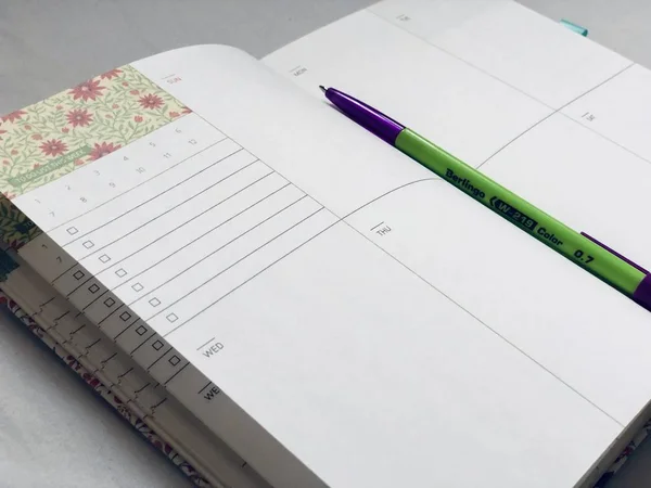 White weekly planner notebook with a pen