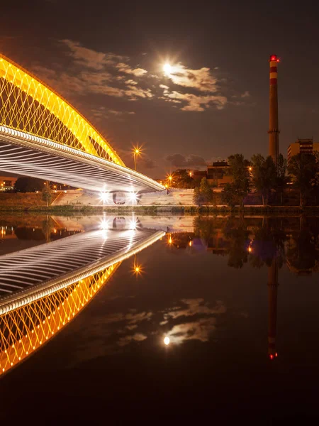 Vltava Nehri üzerindeki modern Troja tramvay köprüsü ve geceleri Prag 'daki fabrika bacası.