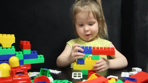 Niña de 3 años jugando con bloques de colores de un constructor. El niño desarrolla sus habilidades de pensamiento. Desarrollo y educación de preescolares . — Vídeos de Stock