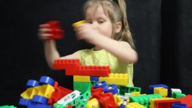 3 yaşında bir kız, bir inşaatçının renkli bloklarıyla oynuyor. Çocuk düşünme becerilerini geliştirir. Anaokullarının geliştirilmesi ve eğitilmesi.