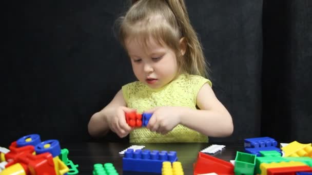 Niña de 3 años jugando con bloques de colores de un constructor. El niño desarrolla sus habilidades de pensamiento. Desarrollo y educación de preescolares . — Vídeos de Stock