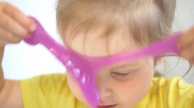 Küçük kız suratının yanındaki balçıkla oynuyor. Yakın plan.