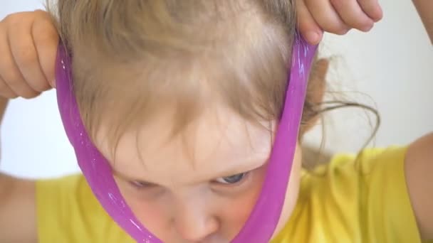 Κοριτσάκι παίζει με γλίτσα κοντά στο πρόσωπο. Κοντινό πλάνο — Αρχείο Βίντεο