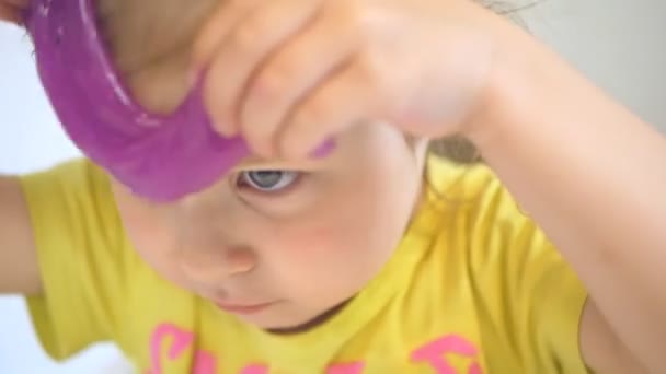 Klein meisje speelt met slijm in de buurt van het gezicht. Close-up — Stockvideo