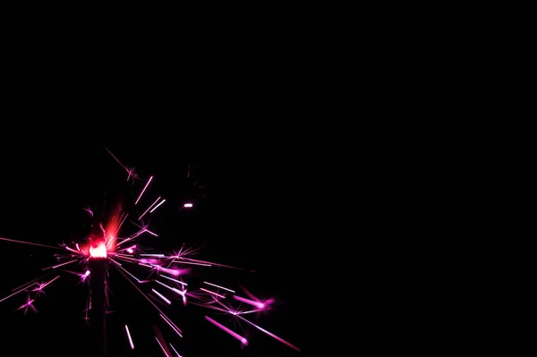 Sparkler in roze en wit licht op een zwarte achtergrond. — Stockfoto