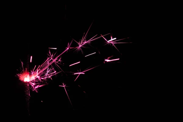 Sparkler em luz rosa e branca sobre um fundo preto . — Fotografia de Stock