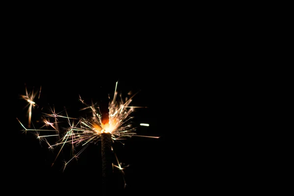 Sparkler in yellow and orange light on a black background. — Stock Photo, Image