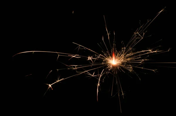 Sparkler em luz amarela e laranja sobre um fundo preto . — Fotografia de Stock