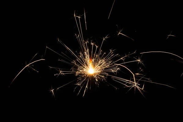 Sparkler in yellow and orange light on a black background. Royalty Free Stock Photos