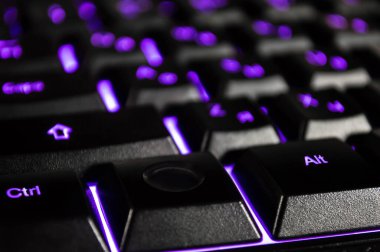 Siyah bilgisayar klavyesinin menekşe arka farlı soyut arkaplanı. Bokeh 'le yakın çekim fotoğrafı, duvar kağıdı gibi kullanılabilir..