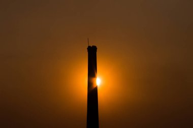 Kule arkasında gün batımı turuncu renklerde. Gün batımı ve karanlık ağaçların fotoğrafı