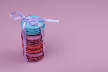 Pembe arka planda renkli Fransız badem kurabiyeleri.