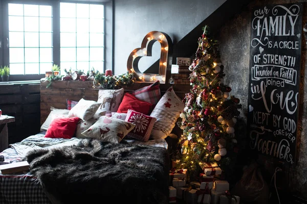 その下にクリスマスプレゼントと美しく装飾された家の中のクリスマスツリー。木はベッドの横に立っている。 — ストック写真