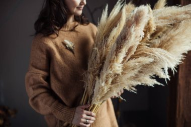 Güzel bir sonbahar buketi, bir kadının ellerinde kurumuş malzemeler. Cortaderia