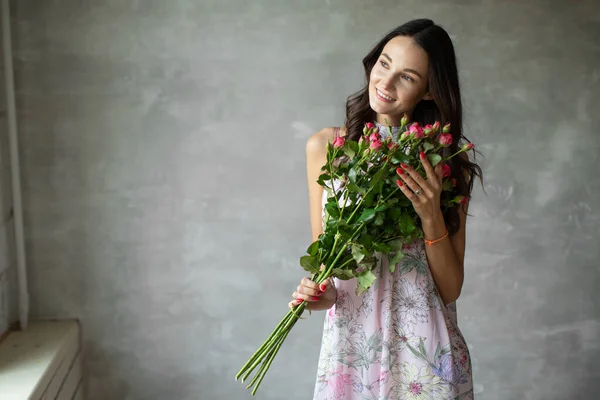Крупный план портрет привлекательной молодой женщины в летнем платье с букетом роз, девушка счастлива — стоковое фото