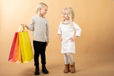 A young girl in a white dress and young boy with shopping bags, happy shopping