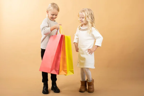 A young girl in a white dress and young boy with shopping bags, happy shopping — 图库照片