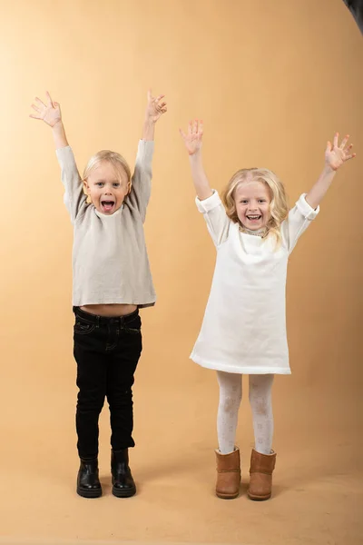 Una niña con un vestido de punto blanco y un sombrero negro y un niño en un suéter. Los niños son felices — Foto de Stock