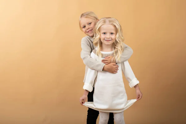 Une petite fille dans une robe blanche tricotée et un chapeau noir et un garçon dans un pull. Garçon câlin une fille — Photo