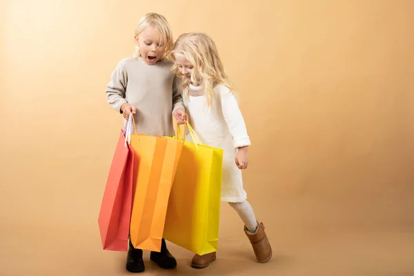 Une jeune fille en robe blanche et un jeune garçon avec des sacs à provisions, heureux shopping — Photo