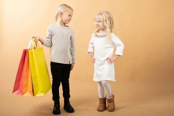 Молода дівчина в білій сукні і молодий хлопчик з сумками, щасливі покупки — стокове фото