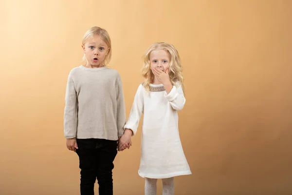 Une petite fille dans une robe blanche tricotée et un chapeau noir et un garçon dans un pull. Les enfants se tiennent la main — Photo